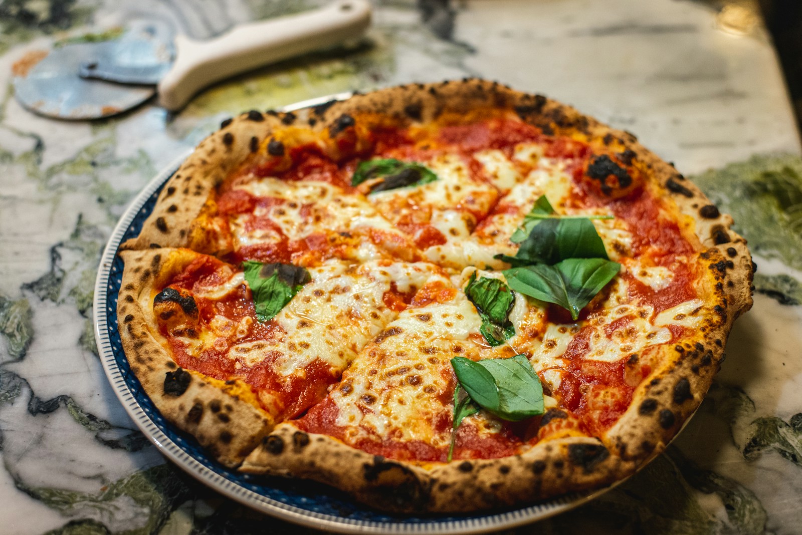 A wood-fired pizza in front of a glowing oven